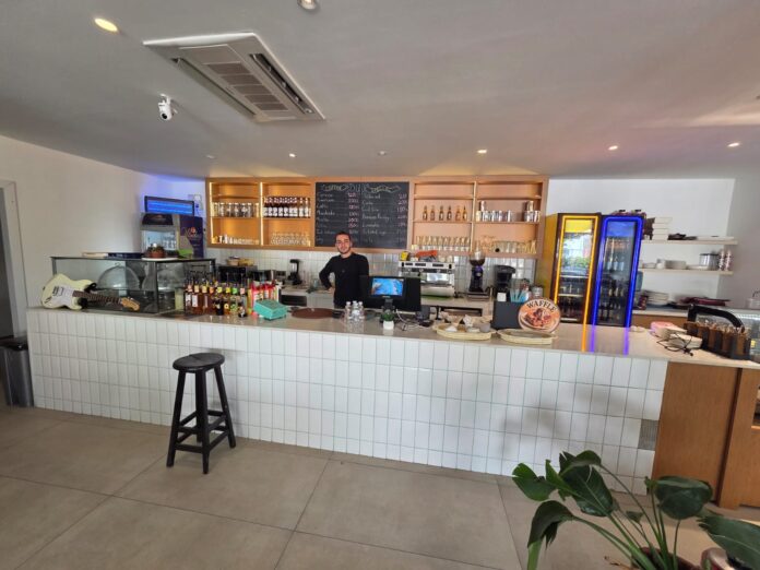 A WARM WELCOME FROM BERAT AT CAFE DUO BODRUM featuring friendly café staff member Berat smiling and welcoming international tourists at a stylish café in Bodrum near the cruise port and marina area.