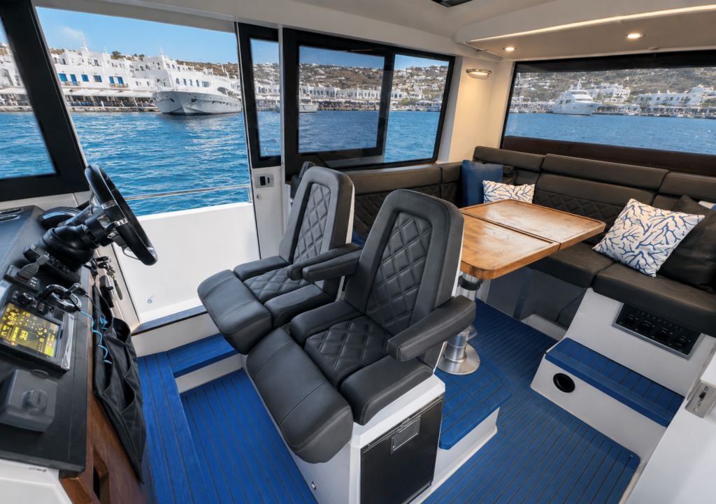 BODRUM TO MYKONOS BY AXOPAR 37 INDOOR luxury cabin interior with premium seating, modern helm station, blue flooring, and panoramic sea views.