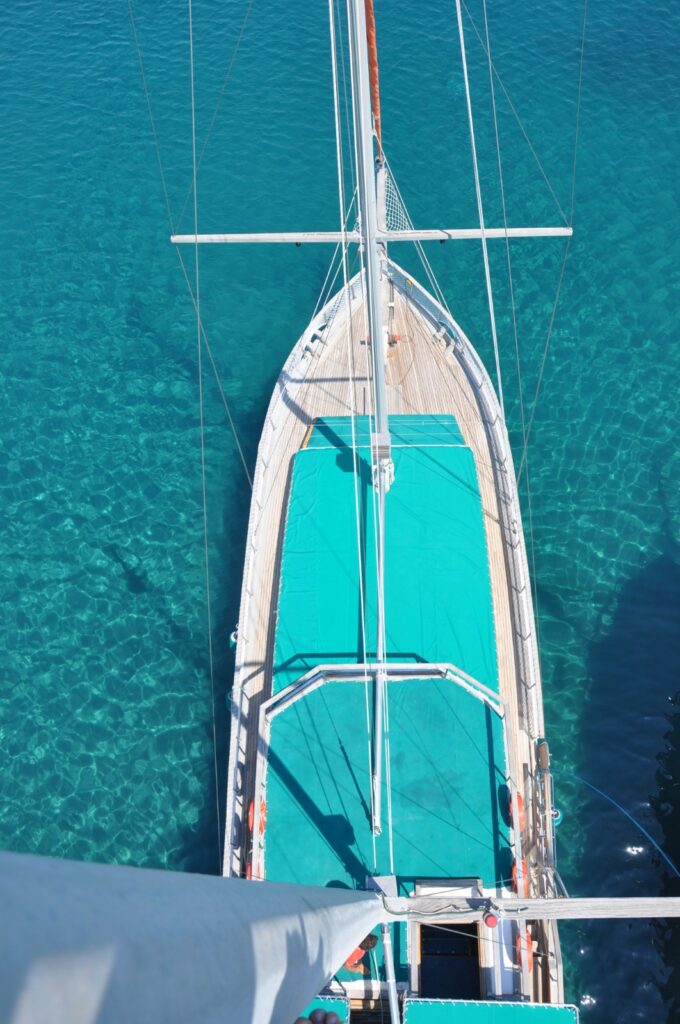 Topal Kamil traditional sailing gulet during a Gümbet Boat Trip in Bodrum, anchored in a crystal-clear turquoise bay with guests relaxing and swimming in the Aegean Sea.