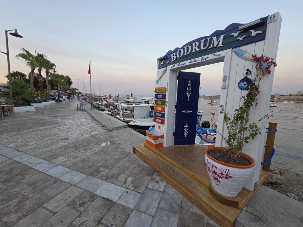 Iconic blue-and-white photo frame in Kumbahçe, Bodrum, overlooking Bodrum Castle and the marina, a popular Instagram photo spot by the sea.