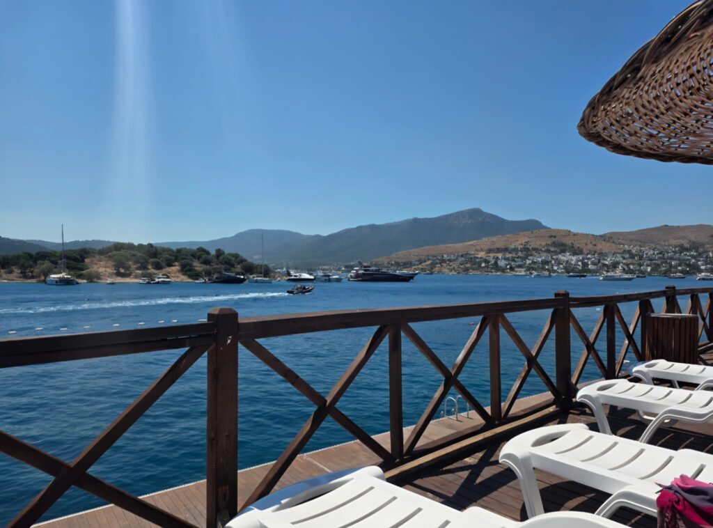 Ministry of Culture and Tourism Türkbükü Public Beach Plastic Sunbeds arranged along the crystal-clear Aegean shoreline, offering comfortable sunbathing with beautiful sea views in Bodrum.